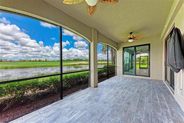 unfurnished sunroom with ceiling fan and a water view