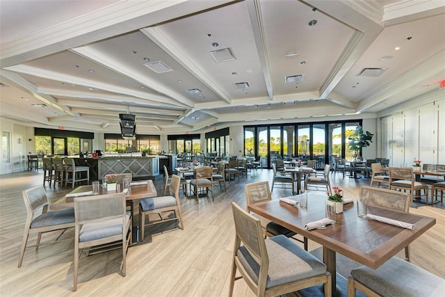 dining area featuring light wood-type flooring, beamed ceiling, and crown molding