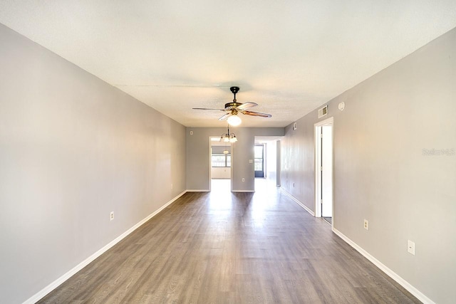 empty room with hardwood / wood-style flooring and ceiling fan with notable chandelier