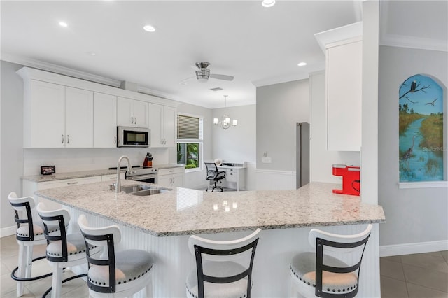 kitchen with decorative light fixtures, light tile patterned flooring, ceiling fan with notable chandelier, sink, and kitchen peninsula