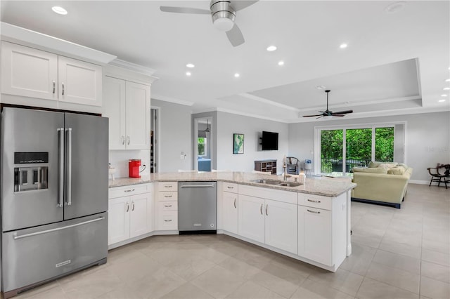 kitchen with white cabinetry, ceiling fan, appliances with stainless steel finishes, a raised ceiling, and ornamental molding