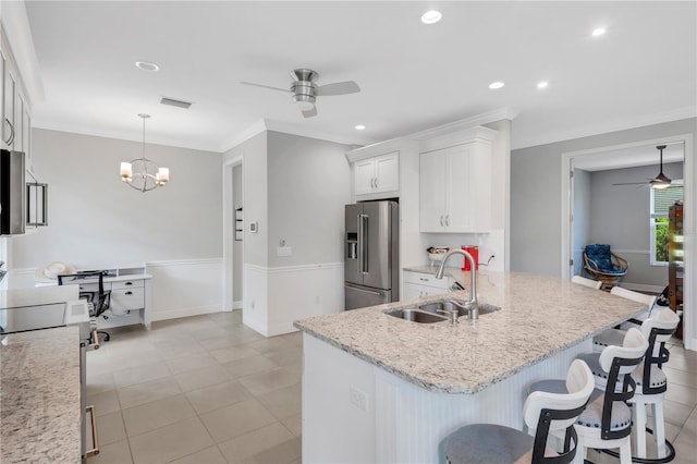 kitchen with high quality fridge, white cabinets, ceiling fan with notable chandelier, and pendant lighting