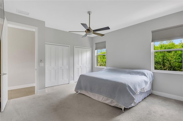 carpeted bedroom with two closets and ceiling fan