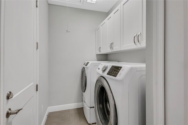 laundry room featuring light tile patterned flooring, cabinets, and washer and dryer