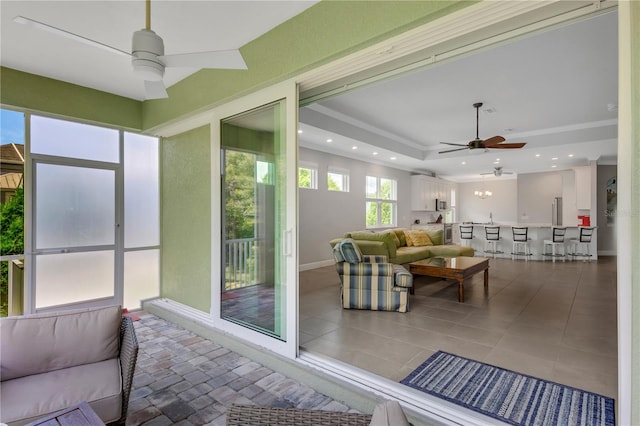 sunroom / solarium featuring a tray ceiling and ceiling fan