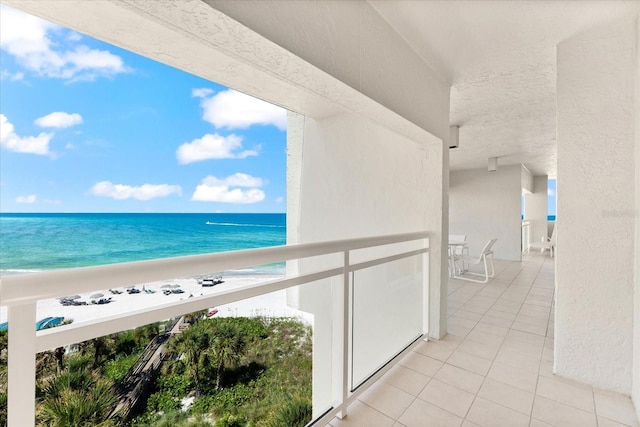 balcony with a water view and a view of the beach