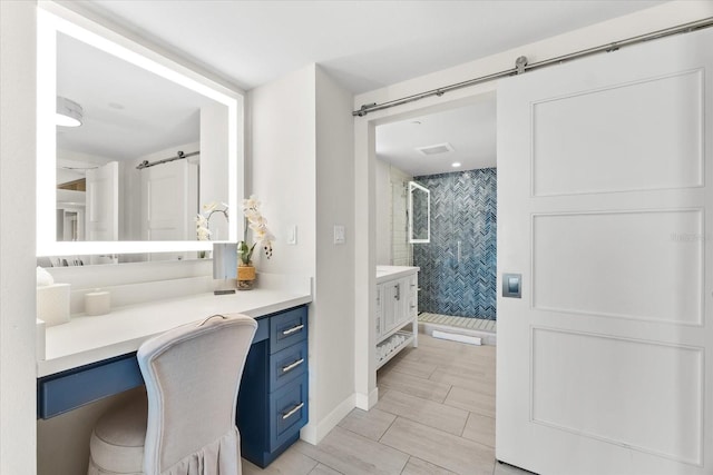 bathroom with a tile shower and vanity