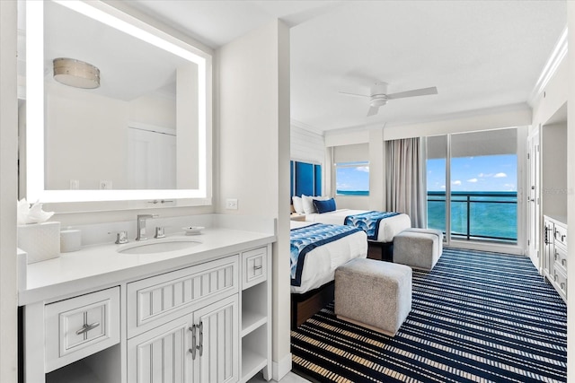 bathroom featuring vanity, a water view, ceiling fan, and crown molding