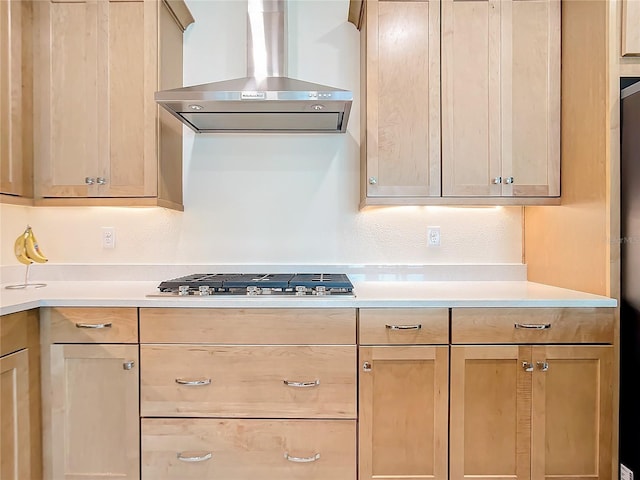 kitchen with light brown cabinets, wall chimney range hood, and stainless steel gas cooktop