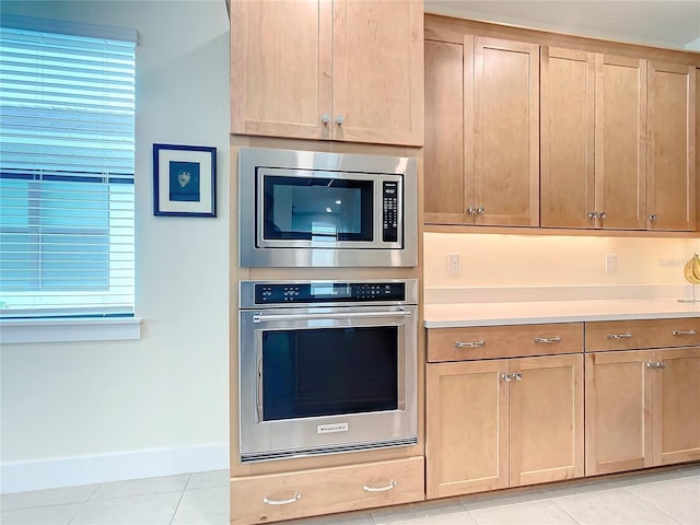 kitchen with a wealth of natural light, light tile patterned floors, and stainless steel appliances