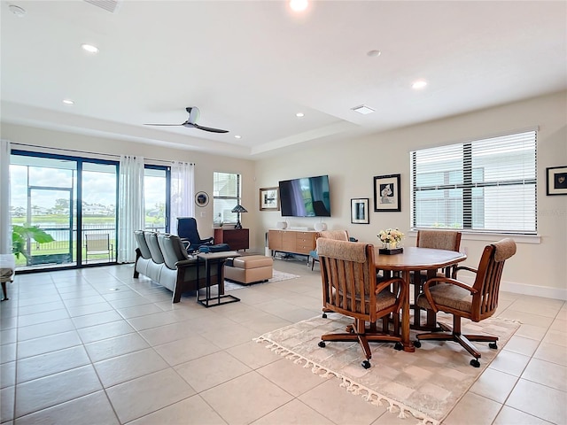 tiled dining space featuring a raised ceiling and ceiling fan