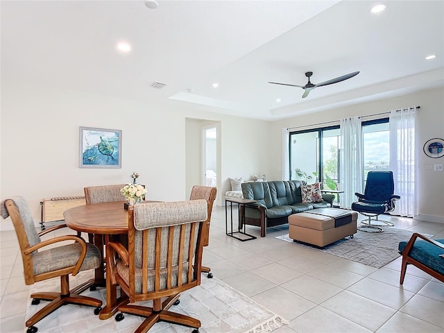 tiled dining room featuring a tray ceiling and ceiling fan