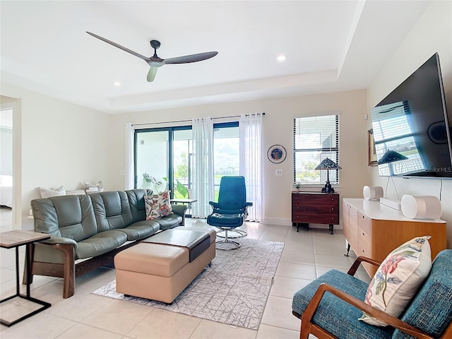 tiled living room featuring a raised ceiling and ceiling fan