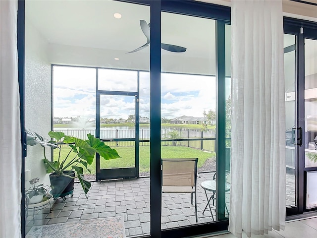 doorway featuring ceiling fan, a water view, and a wealth of natural light