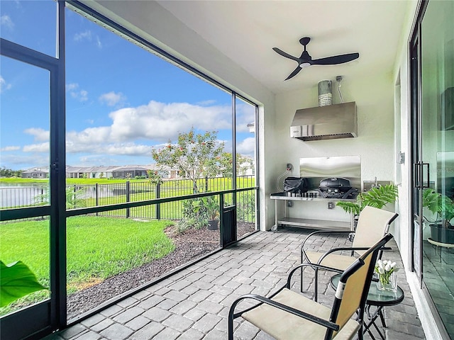 sunroom with a water view, plenty of natural light, and ceiling fan