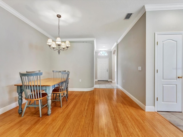 dining room with light wood-type flooring, a chandelier, and ornamental molding