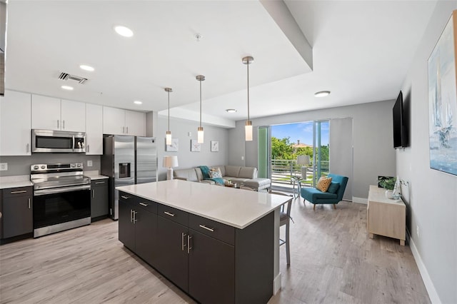 kitchen with light wood-type flooring, open floor plan, a center island, stainless steel appliances, and light countertops