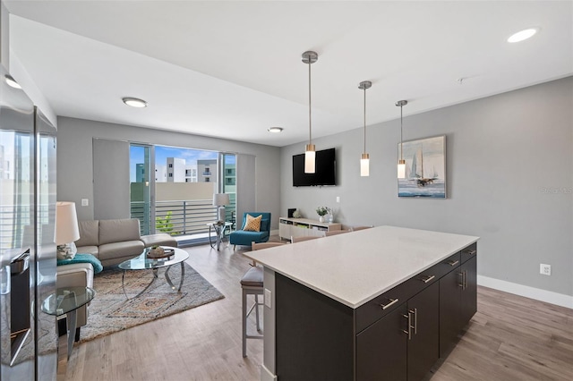 kitchen featuring light wood-style floors, a kitchen island, open floor plan, and light countertops