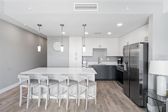 kitchen with visible vents, a kitchen island, light countertops, appliances with stainless steel finishes, and a sink