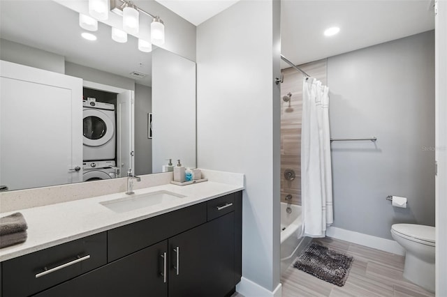 bathroom with visible vents, baseboards, toilet, stacked washer and dryer, and vanity