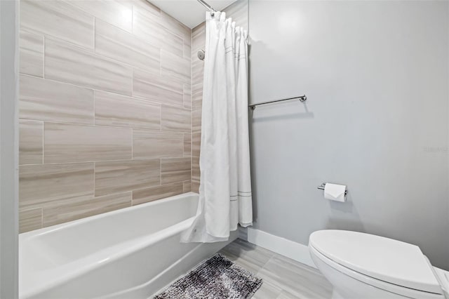 full bathroom with baseboards, toilet, and shower / tub combo