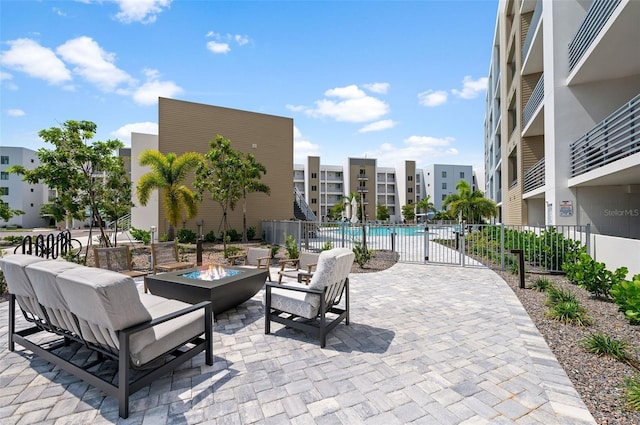 view of patio with a fire pit, fence, and a community pool