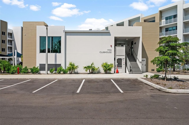 view of building exterior with stairs and uncovered parking