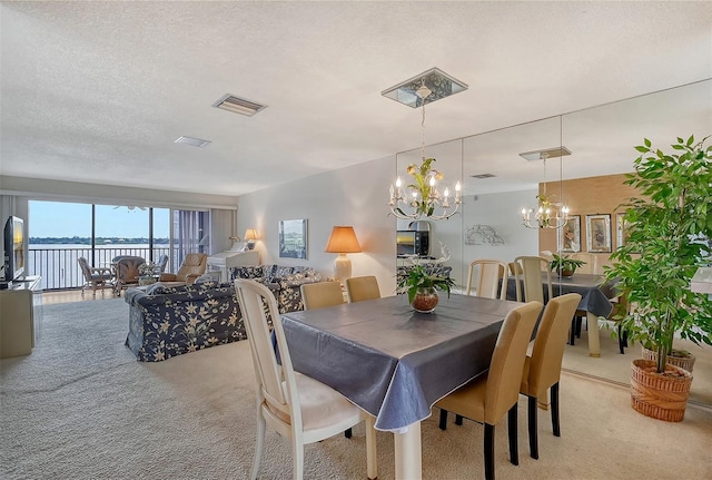 carpeted dining space with a notable chandelier and a textured ceiling