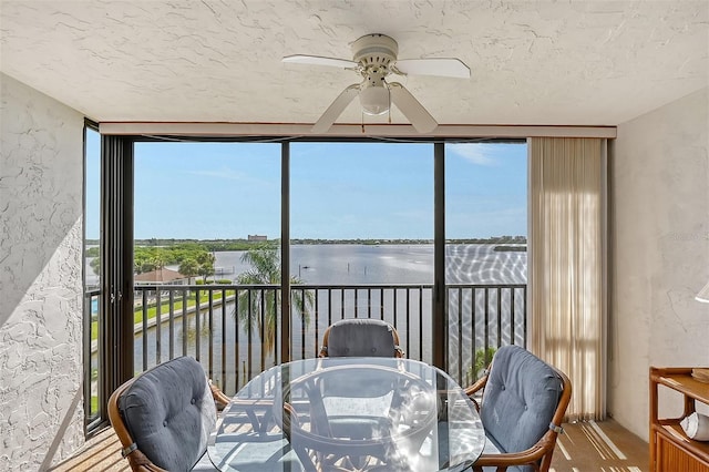 sunroom / solarium featuring a wealth of natural light, ceiling fan, and a water view