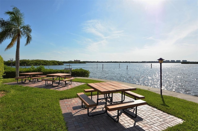 view of property's community featuring a water view, a patio area, and a lawn