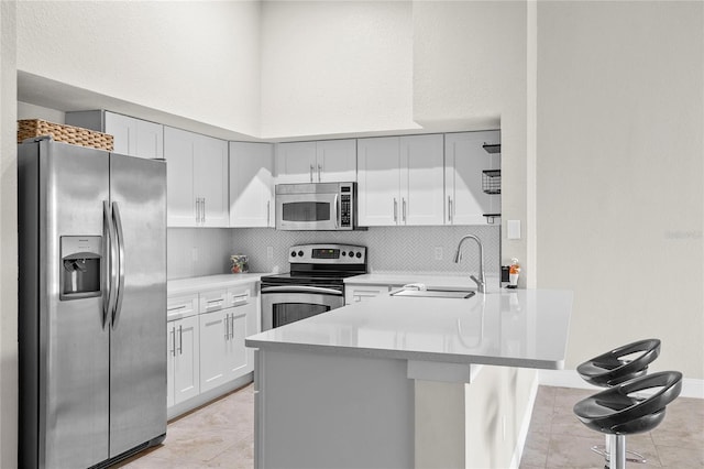 kitchen with a kitchen bar, sink, white cabinetry, appliances with stainless steel finishes, and kitchen peninsula