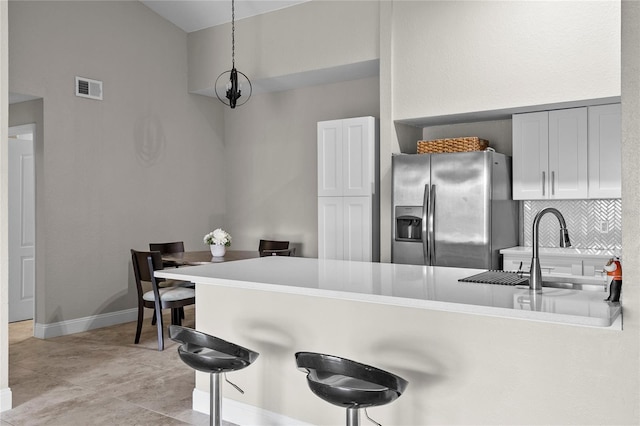 kitchen with pendant lighting, sink, a kitchen breakfast bar, stainless steel fridge with ice dispenser, and kitchen peninsula