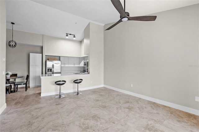 unfurnished living room with ceiling fan, rail lighting, sink, and high vaulted ceiling