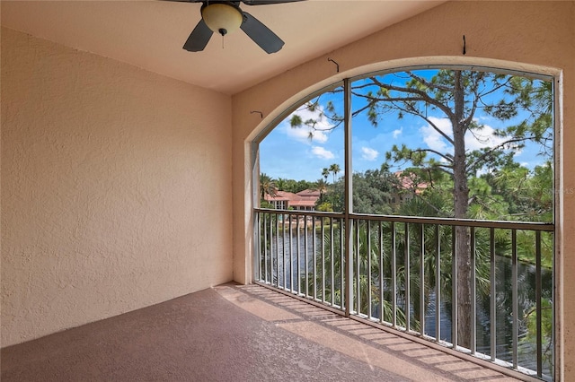 unfurnished sunroom featuring ceiling fan and a water view