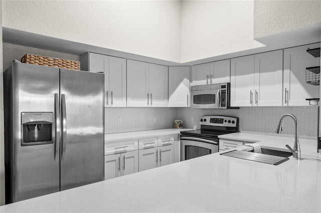 kitchen featuring tasteful backsplash, white cabinetry, appliances with stainless steel finishes, and sink