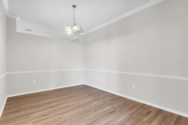 unfurnished room with light hardwood / wood-style floors, an inviting chandelier, and crown molding