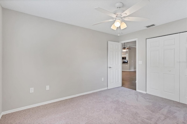 unfurnished bedroom featuring a closet, ceiling fan, and light colored carpet