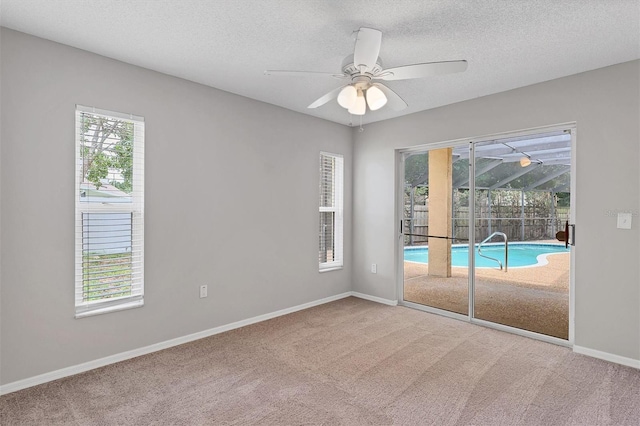 carpeted empty room featuring ceiling fan and a textured ceiling