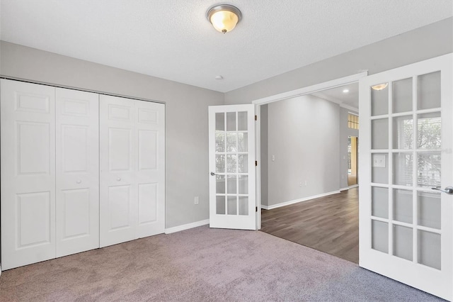 unfurnished bedroom featuring multiple windows, french doors, carpet floors, and a textured ceiling