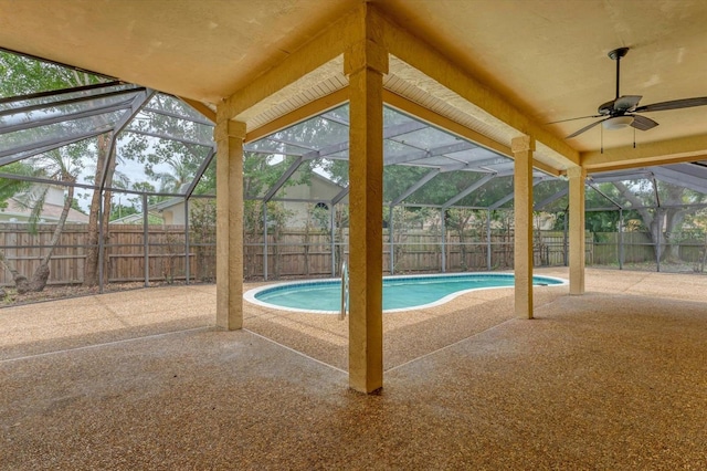 view of swimming pool with glass enclosure, ceiling fan, and a patio area