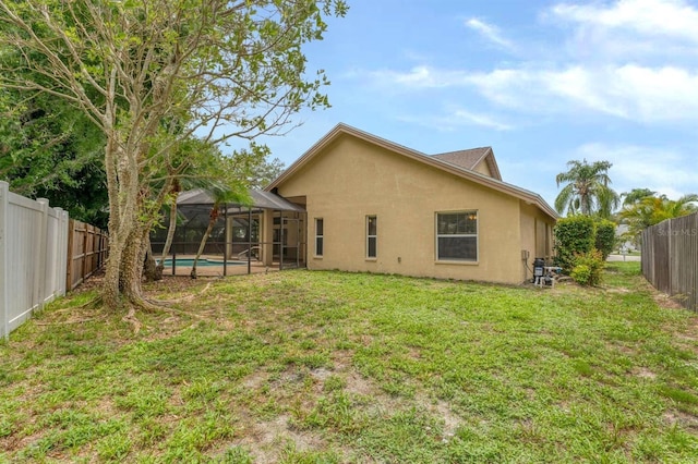 back of property featuring a lanai, a fenced in pool, and a yard