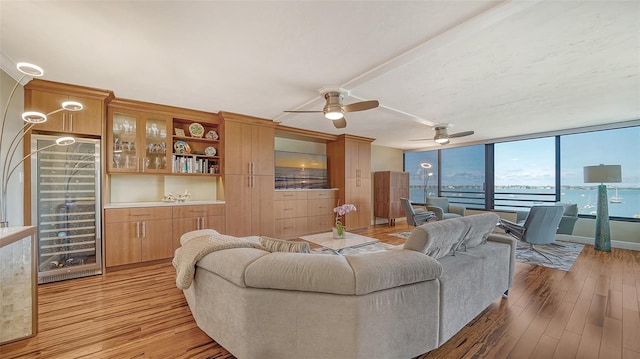 living room featuring a water view, a wall of windows, light hardwood / wood-style floors, and ceiling fan