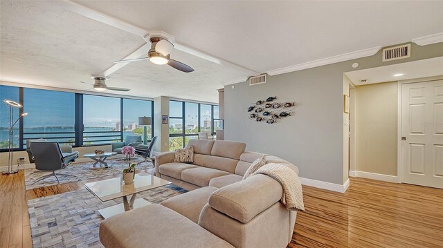 living room featuring ceiling fan, hardwood / wood-style floors, plenty of natural light, and ornamental molding