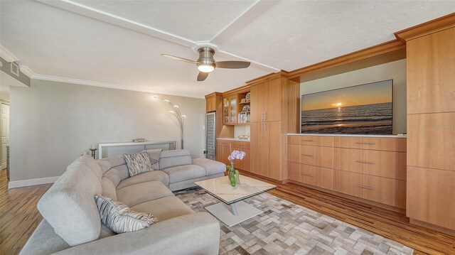 living room with crown molding, ceiling fan, and light hardwood / wood-style floors