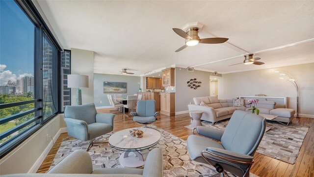 living room featuring ceiling fan, light wood-type flooring, and ornamental molding