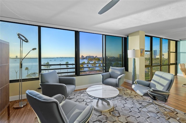 interior space with wood-type flooring, a textured ceiling, a water view, and ceiling fan