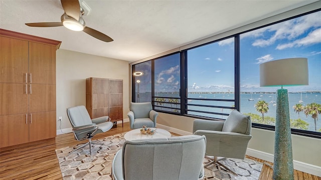 living area featuring a water view, light hardwood / wood-style flooring, and ceiling fan