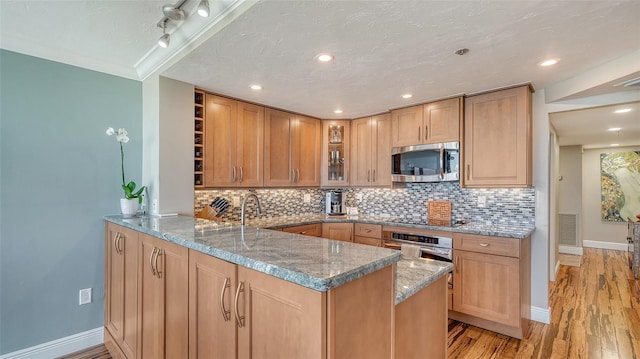 kitchen with light stone countertops, kitchen peninsula, and appliances with stainless steel finishes