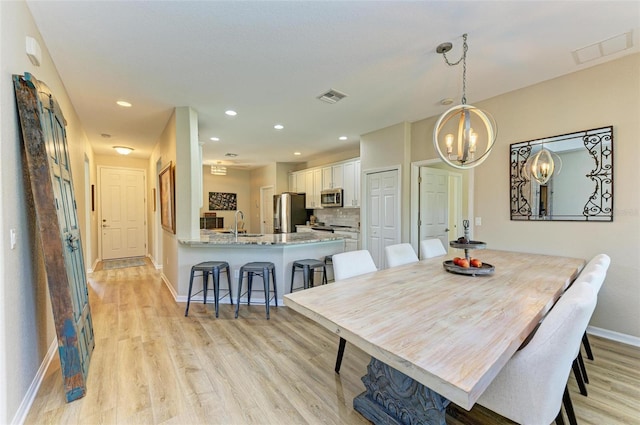 dining room with light wood-type flooring, an inviting chandelier, and sink