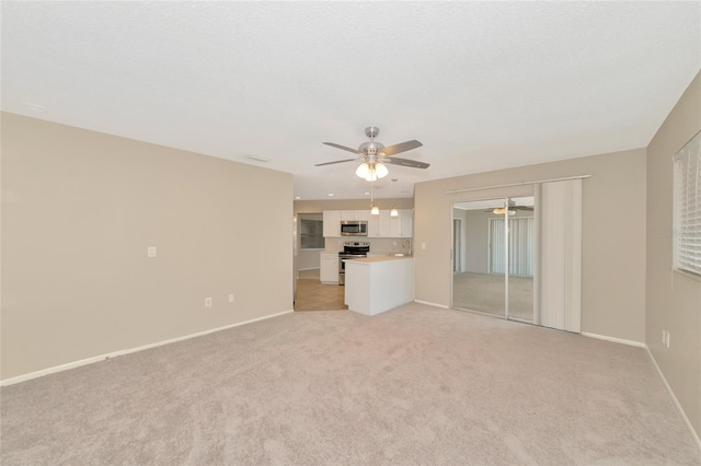 unfurnished living room featuring ceiling fan and light colored carpet